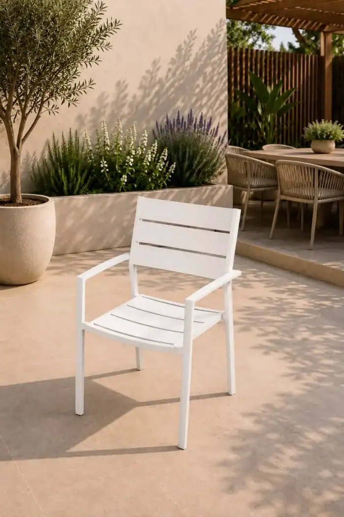 כיסא אפור העשוי 100% אלומיניום (כיסא 100% אלומיניום בצבע אפור) ניצב במרפסת מרוצפת באריחים חומים ליד עץ בעציץ, כשברקע שולחנות גינה ושולחן אוכל חיצוני.